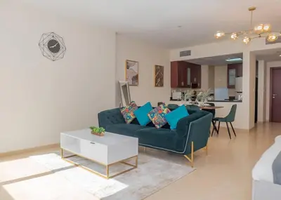 a living room with a blue couch and a table at StoneTree - Studio Apartment Near The Beach in Dubai