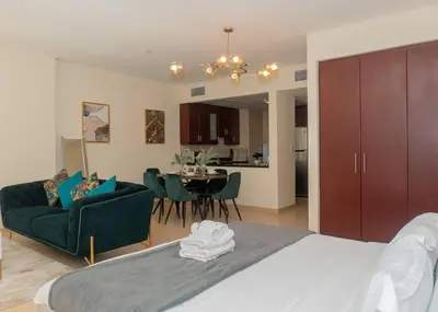 a bedroom with a large bed and a living room at StoneTree - Studio Apartment Near The Beach in Dubai