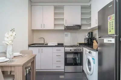 a kitchen with white cabinets and a stainless steel refrigerator at StoneTree - Furnished Studio in Golf Promenade 3A in Dubai