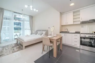 a bedroom with a bed and a table and a kitchen at StoneTree - Furnished Studio in Golf Promenade 3A in Dubai