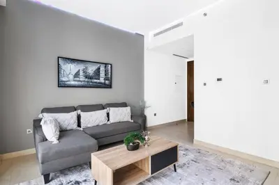 a living room with a couch and a table at StoneTree - Cozy 1 BR in Sobha Hartland Greens 1 in Dubai