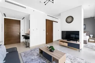a living room with a couch and a tv at StoneTree - Cozy 1 BR in Sobha Hartland Greens 1 in Dubai