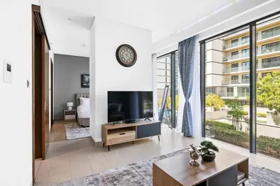 a living room with a tv and a large window at StoneTree - Cozy 1 BR in Sobha Hartland Greens 1 in Dubai
