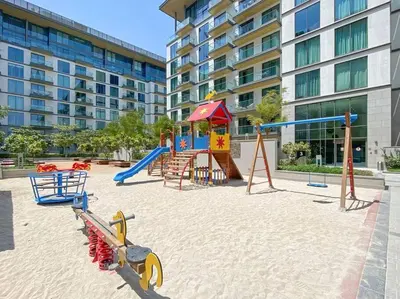 a playground with a slide and play equipment in front of a building at StoneTree - Cozy 1 BR in Sobha Hartland Greens 1 in Dubai