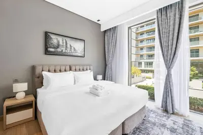 a bedroom with a large white bed and a window at StoneTree - Cozy 1 BR in Sobha Hartland Greens 1 in Dubai