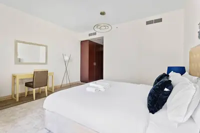 a bedroom with a white bed and a desk at StoneTree - Near Beach - Furnished 1BR with Partial Sea View in Dubai