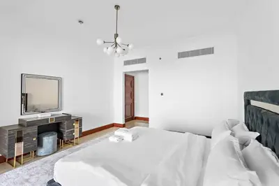 a white bedroom with a bed and a television at StoneTree - 2 BR apartment in Golden Mile 6 Near Nakheel Mall in Dubai