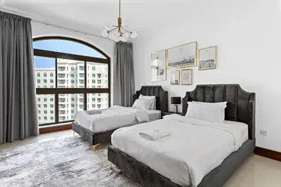 a bedroom with two beds and a large window at StoneTree - 2 BR apartment in Golden Mile 6 Near Nakheel Mall in Dubai