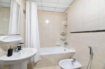 a bathroom with a sink and a toilet and a bath tub at StoneTree - Furnished 1 BR Apartment Near to Tram in Dubai