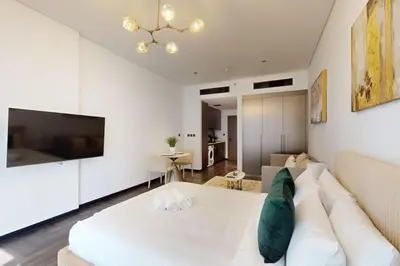 a living room with a white couch and a tv at O Ten, Al Jaddaf - Neat Studio in Dubai