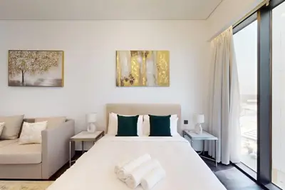 a white bedroom with a large bed and a couch at O Ten, Al Jaddaf - Neat Studio in Dubai