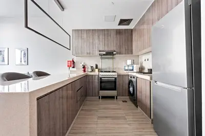 a kitchen with wooden cabinets and a white refrigerator at StoneTree - New stylish 1 BR Apartment in JLT in Dubai