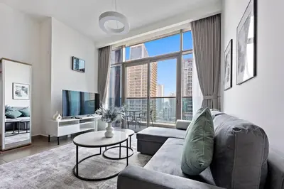 a living room with a couch and a large window at StoneTree - New stylish 1 BR Apartment in JLT in Dubai