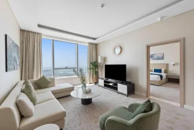 a living room with a couch and a room with a bed at StoneTree - Spacious 1 BR with Stunning Sea View in Palm Jumeirah in Dubai