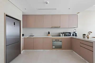 a kitchen with wooden cabinets and a stainless steel refrigerator at StoneTree - Spacious 1 BR with Stunning Sea View in Palm Jumeirah in Dubai