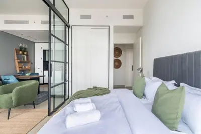 a bedroom with a large white bed and a living room at 2bedroom apartment Dubai Hills in Dubai