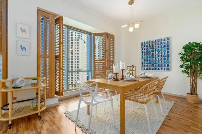 a dining room with a table and chairs and windows at Boutique Apartment Sea Views - Dubai Marina in Dubai