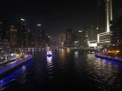 a boat on a river in a city at night at Boutique Apartment Sea Views - Dubai Marina in Dubai