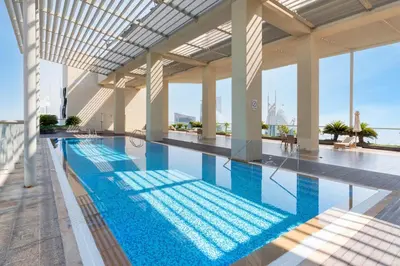 a large swimming pool with blue water in a building at Upgraded 1BR on a high floor of Liberty House,DIFC - Allsopp&Allsopp in Dubai
