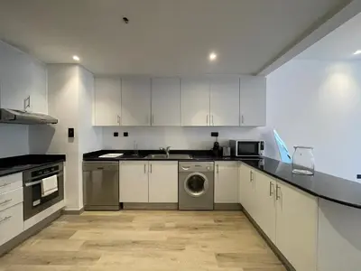a kitchen with white cabinets and a washing machine at Deluxe 1 Bedroom Apartment - Elite Residence Dubai Marina - Sea View in Dubai