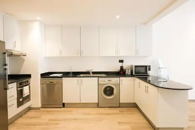 a kitchen with white cabinets and a washing machine at Deluxe 1 Bedroom Apartment - Elite Residence Dubai Marina - Sea View in Dubai
