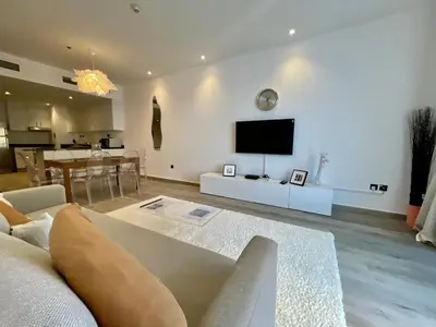 a living room with a couch and a tv on a wall at Deluxe 1 Bedroom Apartment - Elite Residence Dubai Marina - Sea View in Dubai