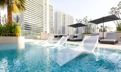two white chairs and umbrellas in a swimming pool at Exclusive Offer Cozy Stay with Burj Khalifa Views by Deluxe Holiday Homes in Dubai