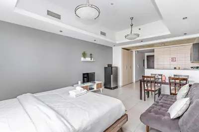 a bedroom with a bed and a couch and a kitchen at StoneTree - Near Metro - Furnished Studio in JLT in Dubai