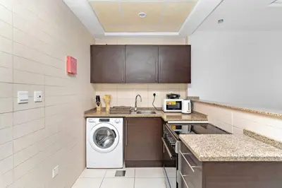 a kitchen with a washing machine and a sink at StoneTree - Near Metro - Furnished Studio in JLT in Dubai