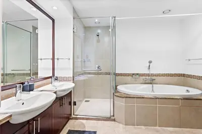 a bathroom with two sinks and a shower and a tub at StoneTree - Elegant 2BR with 1 Maids Room in Dubai