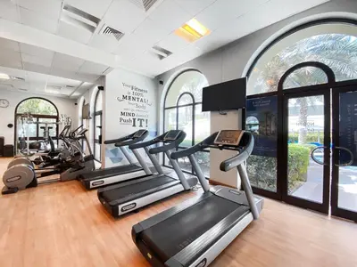 a gym with several treadmills and elliptical machines at StoneTree - Elegant 2BR with 1 Maids Room in Dubai