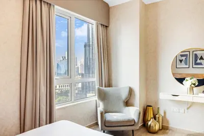 a hotel room with a chair and a large window at Durrani Homes - Grandiose 5BR Besides Dubai Mall with Burjkhalifa and Fountain view in Dubai