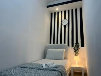a bedroom with a bed and a clock on the wall at Strips Partition Room Al barsha 1 Near MOE Metro in Dubai