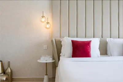 a bedroom with a white bed with a red pillow at Durrani Homes - Lavish 3BR Besides Burj Khalifa and Fountain view in Dubai