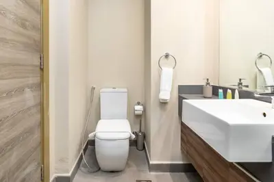 a bathroom with a white toilet and a sink at Bloom Heights: Pool, Gym & Wi-Fi - JVC - Dubai in Dubai