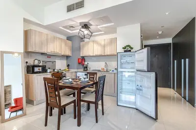 a kitchen with a table and chairs and a refrigerator at Bright & Elegant Studio Balcony Speedy Wi-Fi in Dubai