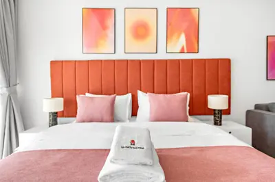 a bedroom with a large bed with pink pillows at StoneTree - Modern Stylish Studio in JLT in Dubai