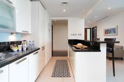 a kitchen with white cabinets and a black counter top at Lovely Lake View - Two Bedroom - JLT in Dubai
