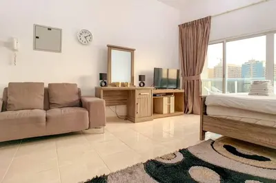 a living room with a couch and a bed and a mirror at StoneTree - Furnished Studio in Peaceful Location in Dubai