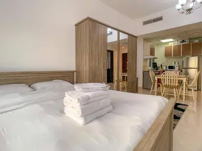 a bedroom with a white bed with towels on it at StoneTree - Furnished Studio in Peaceful Location in Dubai