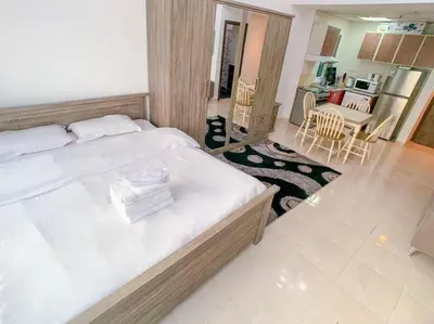 a bedroom with a large bed and a kitchen at StoneTree - Furnished Studio in Peaceful Location in Dubai