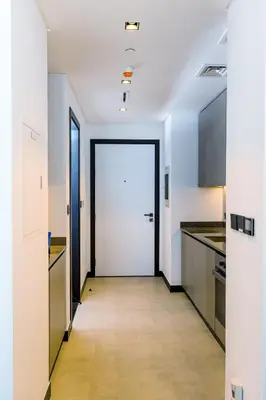 a hallway of a kitchen with a white door at Cozy Studio whit balcony 15NS in Dubai