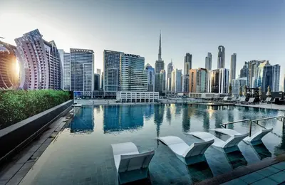 a pool with white chairs and a city skyline at Cozy Studio whit balcony 15NS in Dubai