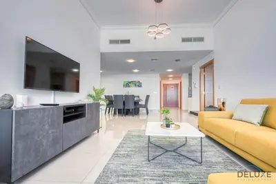 a living room with a yellow couch and a tv at Exquisite 3BR at Ocean Heights Dubai Marina by Deluxe Holiday Homes in Dubai