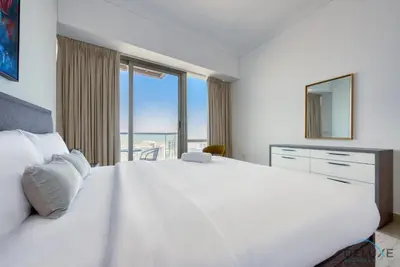 a white bedroom with a large bed with a large window at Exquisite 3BR at Ocean Heights Dubai Marina by Deluxe Holiday Homes in Dubai