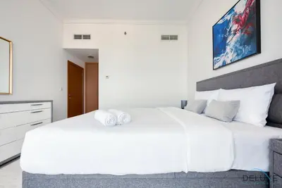 a bedroom with a large white bed with two towels on it at Exquisite 3BR at Ocean Heights Dubai Marina by Deluxe Holiday Homes in Dubai