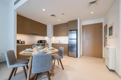 a kitchen with a table and chairs and a refrigerator at Modern 1 Bedroom Apartment I Creek Beach I Surf in Dubai