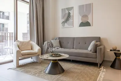 a living room with a couch and a table and a chair at Modern 1 Bedroom Apartment I Creek Beach I Surf in Dubai