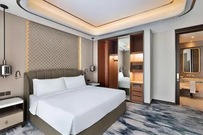 a bedroom with a white bed and a bathroom at Embassy Suites By Hilton Dubai Business Bay in Dubai