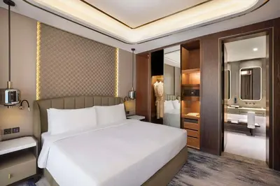 a bedroom with a large white bed and a bathroom at Embassy Suites By Hilton Dubai Business Bay in Dubai